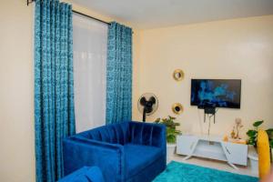 a living room with a blue chair and a television at Belch Apartment in Kisumu