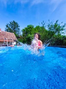 a young boy is splashing in a swimming pool at Aracsa Farm és Vendégház Kis Balaton és termál fürdők in Egeraracsa