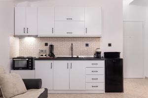a kitchen with white cabinets and a black refrigerator at Luxury Central Apartment 2 in Xanthi