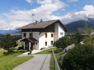 una pequeña casa blanca en una colina con una carretera en Huber - Das Tiroler B&B en Oberperfuss