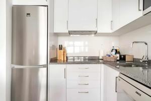 a kitchen with white cabinets and a stainless steel refrigerator at Timeless Beach I Apartment in Armação de Pêra