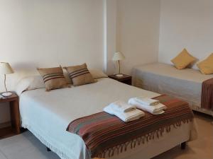 two beds in a room with towels on a bench at Nono Huasi Departamentos in Cafayate