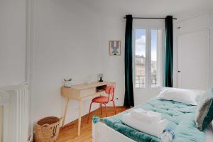 敘雷納的住宿－Cozy 2-Bedroom Apartment in the Heart of Suresnes，一间卧室配有一张桌子和一张床,一张桌子和椅子