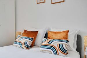 a white bed with four pillows on it at Cozy 2-Bedroom Apartment in the Heart of Suresnes in Suresnes