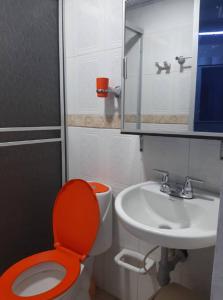 baño con aseo rojo y lavamanos en Confortable Apartamento Central, en Tame