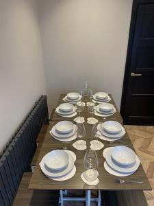 a long wooden table with plates and wine glasses at Luxury Home in Blackpool in Blackpool