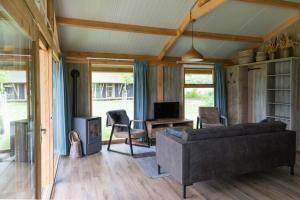 een woonkamer met een bank en een tafel met een tv bij Special tent lodge with dishwasher, in Twente in Buurse