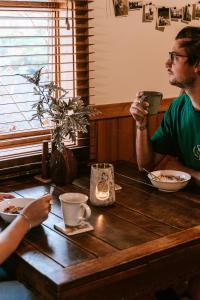 a man sitting at a wooden table with a woman at Hideaway Farmlet Romantic Cottage with Miniature Goats in Penguin