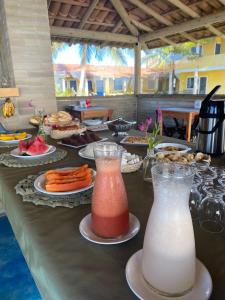 una mesa con platos de comida y dos recipientes de zumo en Quintal da Praia, en Prado