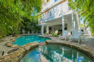 una piscina en el patio trasero de una casa con 2 sillas en Coral Retreat, en Holmes Beach