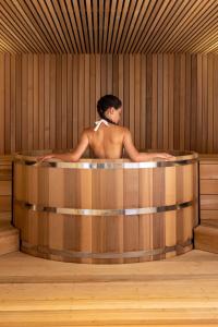 una mujer sentada en una bañera en una habitación de madera en Maison Rouge Strasbourg Hotel & Spa, Autograph Collection en Estrasburgo