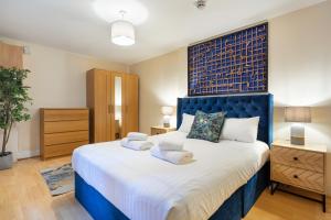 a bedroom with a large bed with a blue headboard at Elegant Kensington Apartment with patio in London