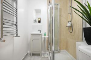 ein Bad mit einer Dusche und einem Waschbecken in der Unterkunft Elegant Kensington Apartment with patio in London