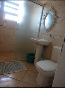 uma casa de banho com um WC, um lavatório e um espelho. em Apartamento Paraíso A Beira Mar em Torres