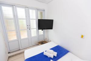 a room with a bed and a tv on a window at Wafeh Fleming Suítes Pampulha in Belo Horizonte