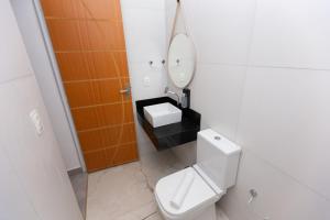 a bathroom with a toilet and a sink and a mirror at Wafeh Fleming Suítes Pampulha in Belo Horizonte