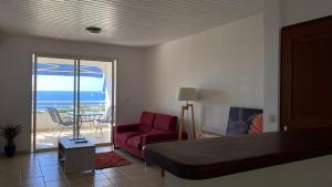 a living room with a red couch and a balcony at Appartement F3 Vue Mer in Case-Pilote