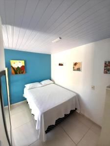 Suítes Brisa Tropical في كابو فريو: غرفة نوم بسرير ابيض بجدار ازرق