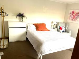 a bedroom with a white bed and a dresser at MarinaView room with private bathroom in Auckland