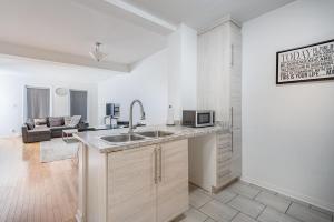 a kitchen with a sink and a living room at AAA Location Condo & FREE Parking in Montreal