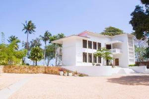 MaziziniにあるThe Cliff Beach Apartmentのヤシの木が背景に広がる白い家