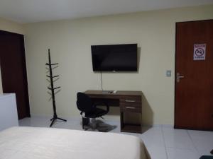 a bedroom with a desk and a television on a wall at Pousada Espaco Luz do Sol Beira-Mar in João Pessoa