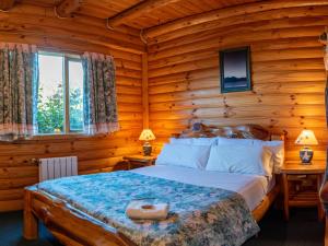 1 dormitorio con 1 cama en una cabaña de madera en Hostería Epulén en Villa La Angostura
