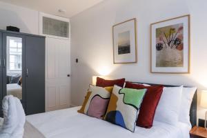 um quarto com uma cama branca e almofadas coloridas em kings cross St Pancras luxury apt em Londres