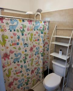 a bathroom with a shower curtain with dinosaurs on it at La Casa de Don Carlos in Usulután