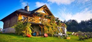 una casa in legno con edera sul lato di Winnica Nad Źródłem - Domki w winnicy z kominkami i tężniami a Sierzawy