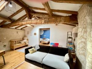 een woonkamer met een bank en een loft bij Les Régniers - 2 gîtes entre vignobles et forêts, proche Dordogne in Eynesse