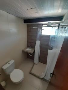 uma casa de banho com um WC e uma cortina de chuveiro em Suítes Brisa Tropical em Cabo Frio