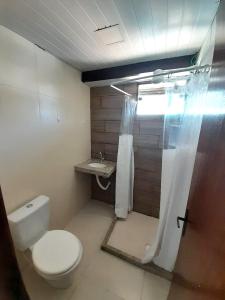 y baño con aseo y cortina de ducha. en Suítes Brisa Tropical en Cabo Frío