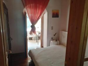 een slaapkamer met een bed en een raam met een rood gordijn bij Parnassos cottage 