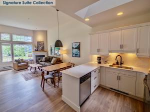 uma cozinha e sala de estar com armários brancos e uma mesa em Waters Edge Shoreside Suites em Ucluelet