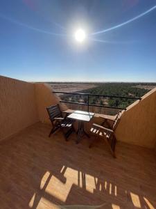 einen Balkon mit Tisch, Stühlen und Sonne in der Unterkunft Palms Garden in Erfoud