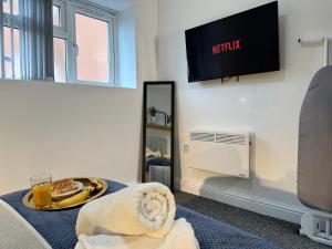 a room with a television and a table with a plate of food at Charming Studio Apartment with Netflix in Birmingham