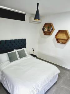 um quarto com uma cama branca e uma cabeceira azul em Departamento en el Norte de Mérida em Mérida