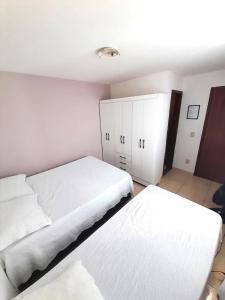 um quarto com 2 camas e armários brancos em Suítes Brisa Tropical em Cabo Frio