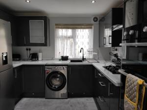 a kitchen with a washing machine in the middle at Elegant 3-Bedroom Home, sleeps up to 5 guest. in South Ockendon