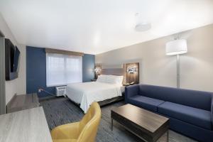 une chambre d'hôtel avec un lit et un canapé bleu dans l'établissement Holiday Inn Express & Suites Zion, an IHG Hotel, à Zion