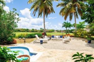 a backyard with a swimming pool and palm trees at Golf Villa en Casa de Campo in Cajuiles