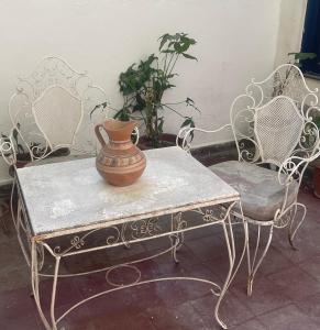 un jarrón sentado en una mesa con dos sillas en Casa Céntrica totalmente equipada !!! en Santiago del Estero