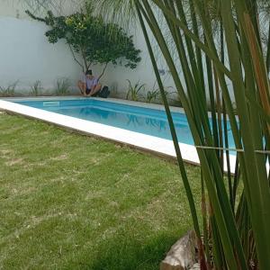 un hombre está sentado junto a una piscina en Güemes Hostel Cordoba en Córdoba