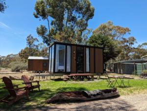 Dadswells BridgeTiny House 10 at Grampians Edge的一座带玻璃墙和木柴的小房子