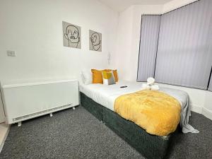 a bedroom with a large bed with a yellow blanket at Cosy, fresh studio with Netflix in Kidderminster