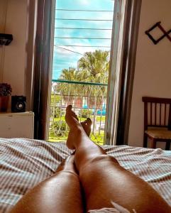 a dog laying on a bed looking out a window at Pousada Solar Colonial in Iguape