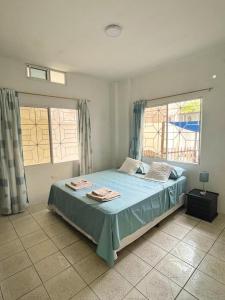 a bedroom with a bed with blue sheets and two windows at Lara's House in Puerto Ayora