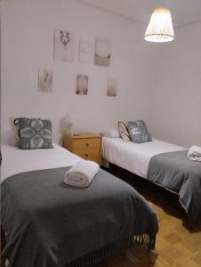 a bedroom with two beds and a lamp and pictures on the wall at Apartamento a 10 minutos de la Calle Laurel in Logroño