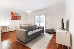 a living room with a couch and a tv at Cascais Beach Flower Apartment in Estoril
